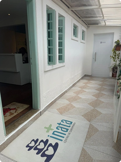 Entrada interna da Inata Quiropraxia e Bem-Estar com tapete personalizado e ambiente claro.