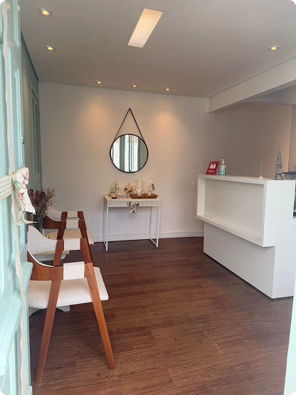 Vista geral da recepção da Inata Quiropraxia e Bem-Estar com mesa de café e espelho decorativo.