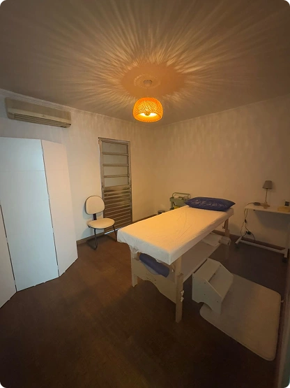 Sala com maca de atendimento, iluminação suave e decoração minimalista.